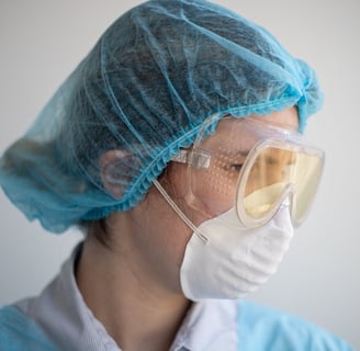 a woman in a blue scrub suit and goggles