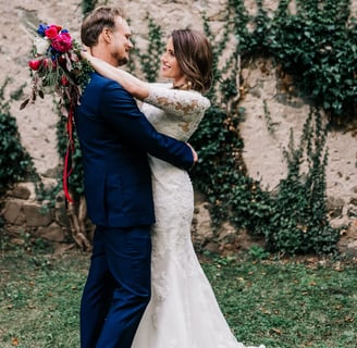 a bride and groom standing in front of a stone wall