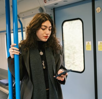 A woman standing on a train looking at her cell phone.