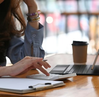 A woman sitting at a desk, holding a pen,  and working on a calculator