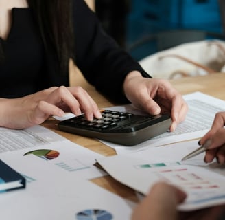 a woman is sitting at a desk with a calculator and graph charts