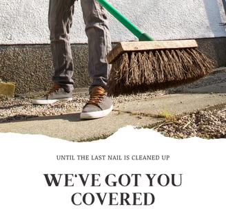 A worker sweeping up a job site at the end of a job in jeans and sneakers