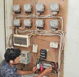 a man in a blue shirt is working on a electrical panel