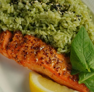 a plate of food with salmon, rice and a lemon wedge