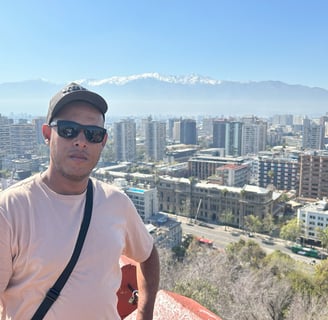 uma pessoa de óculos escuro de costa para a cidade e no fundo as cordilheiras dos andes no chile