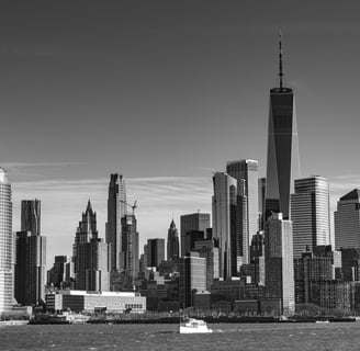 A black and white photo of New York City skyline taken from the Hudson River. in the forground is a pleasure boat passing