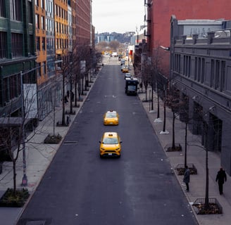 two yellow taxis drive down the centre of an empty new york city street