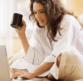 Woman comfortable at home on laptop with coffee mug, researching fertility options