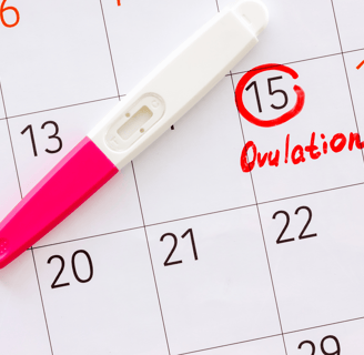 Ovulation test placed on calendar with cycle day marked in red