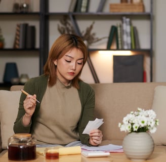 Woman calculating IVF costs at home with documents and calculator