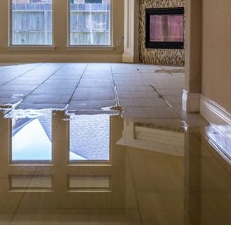 Flooded tiled living room with water damage after a plumbing failure, illustrating the risks of delayed insurance claims.