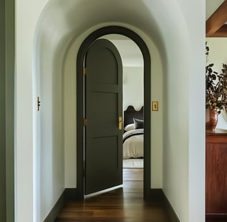 Arched dark green bedroom door with gold hardware