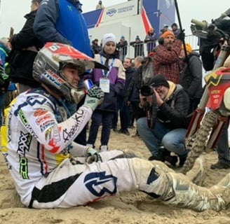 a man sitting on a dirt bike in the sand