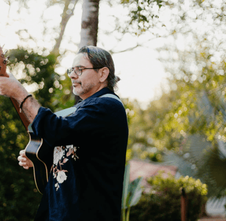a man playing guitar in a backyard