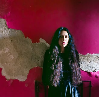 a woman in a black dress standing in front of a pink wall