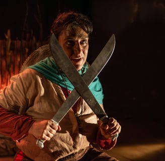 a man in a brown jacket holding two large knives