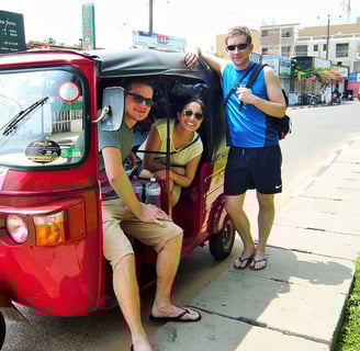 three people standing around a red tuk tuk tuk