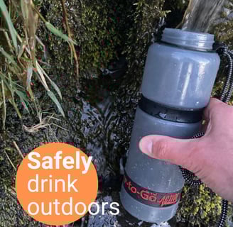 a person holding a water bottle and drinking from a water bottle