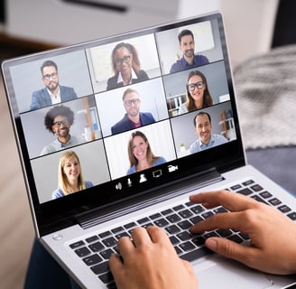 A person with a laptop participating in a virtual team meeting