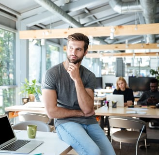 a man sitting at a table with an open laptop in an office