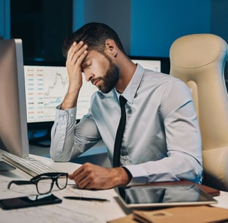 Stressed businessman sitting at his desk with his head in his hand