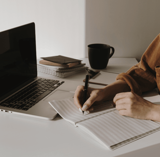 Persona che scrive su un quaderno in modo riflessivo, simbolo di scrittura CREATIVA, journaling