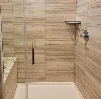 Sparkling clean shower with polished tile walls, fixtures, and glass door.