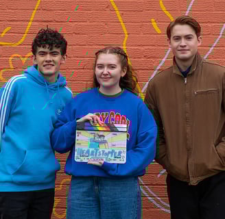 Alice Oseman holds heartstopper slate and poses with Joe Locke and Kit Connor