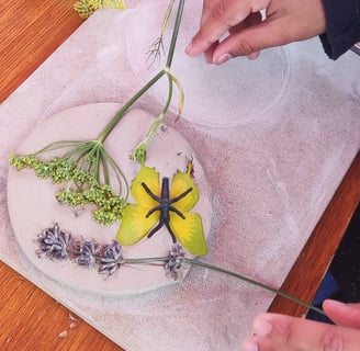 a person pressing flowers in to clay on a wooden board