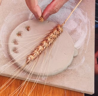a person pressing a wheat ear into clay
