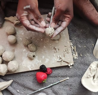 a woman is making clay fruit
