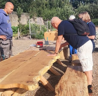 a people standing in front of a wooden bench with a bench and table