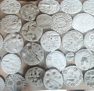 a bunch of clay tiles with different plants pressed in
