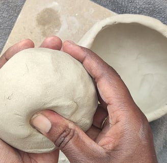 a person shaping a ball of clay in their hands