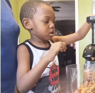 Child juicing fruit with patent supervising.