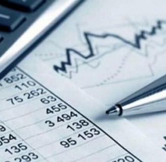 Calculadora e caneta sobre papeis com números, demonstrando análises de contas.