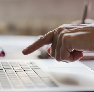 Mão apontando para o teclado de notebook