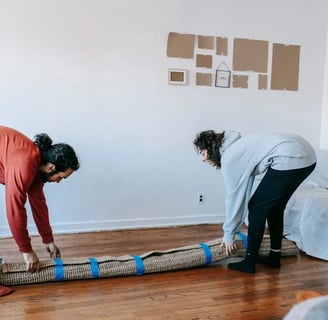 two people handling a packed rug