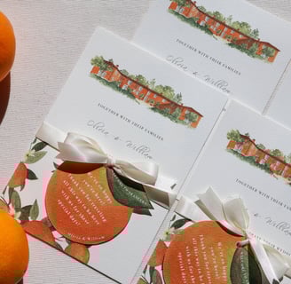 a bunch invitations with the orange house and some oranges on a table