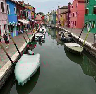 pequenos barcos ancorados em canal e casinhas coloridas em volta