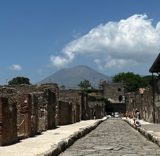 visitantes em uma ruela de Pompeia com o monte Vesúvio ao fundo