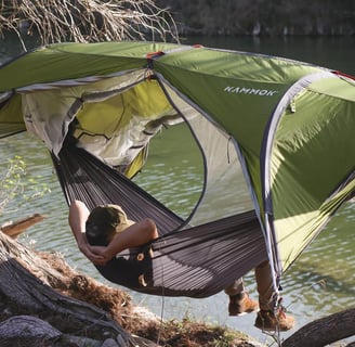a person sitting in a hammock with a tent
