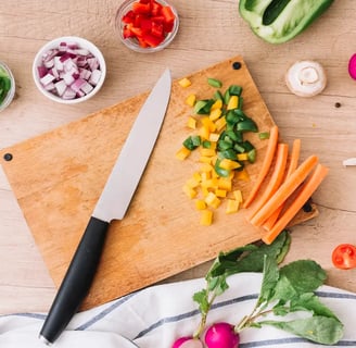 Chopped vegetables on a cutting board with a knife.