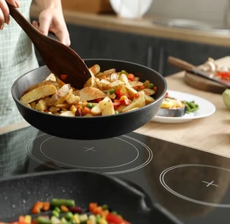 Person stirring roasted vegetables in a pan in a modern kitchen.