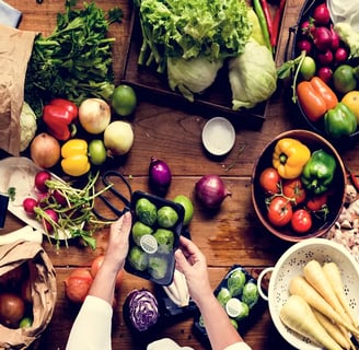 Fresh vegetables including peppers, onions, and Brussels sprouts on a wooden table.