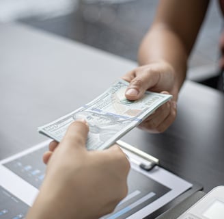 a person holding a money bill and a laptop