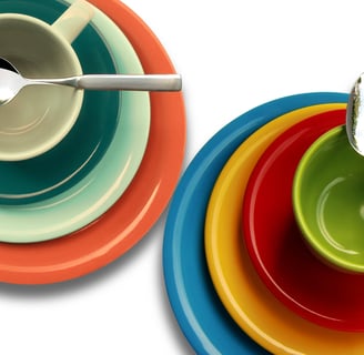 Different sized plates, two cups in orange, light green, green, blue, yellow, and red colors spoons