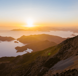 a mountain scene with a sunset over the ocean