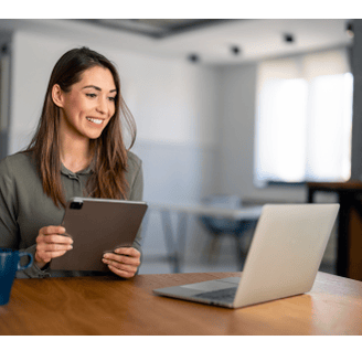 Life coach holding a tablet and looking at a laptop.