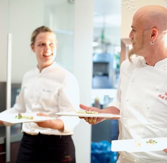 Ralf Zacherl holding two plates looking at a waitress.